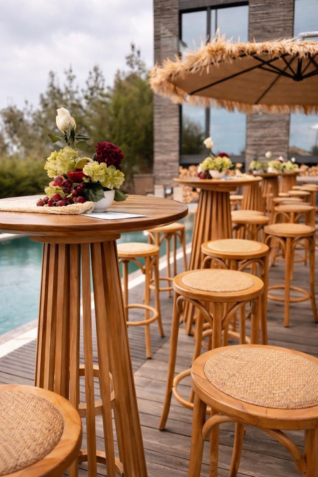 Mesas altas de madera junto a la piscina